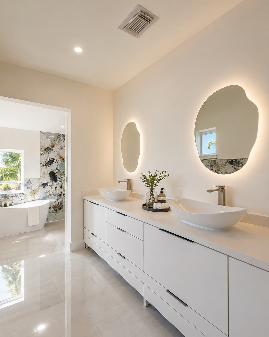 Remodeled bathroom with a double vessel-sink vanity and backlit mirrors